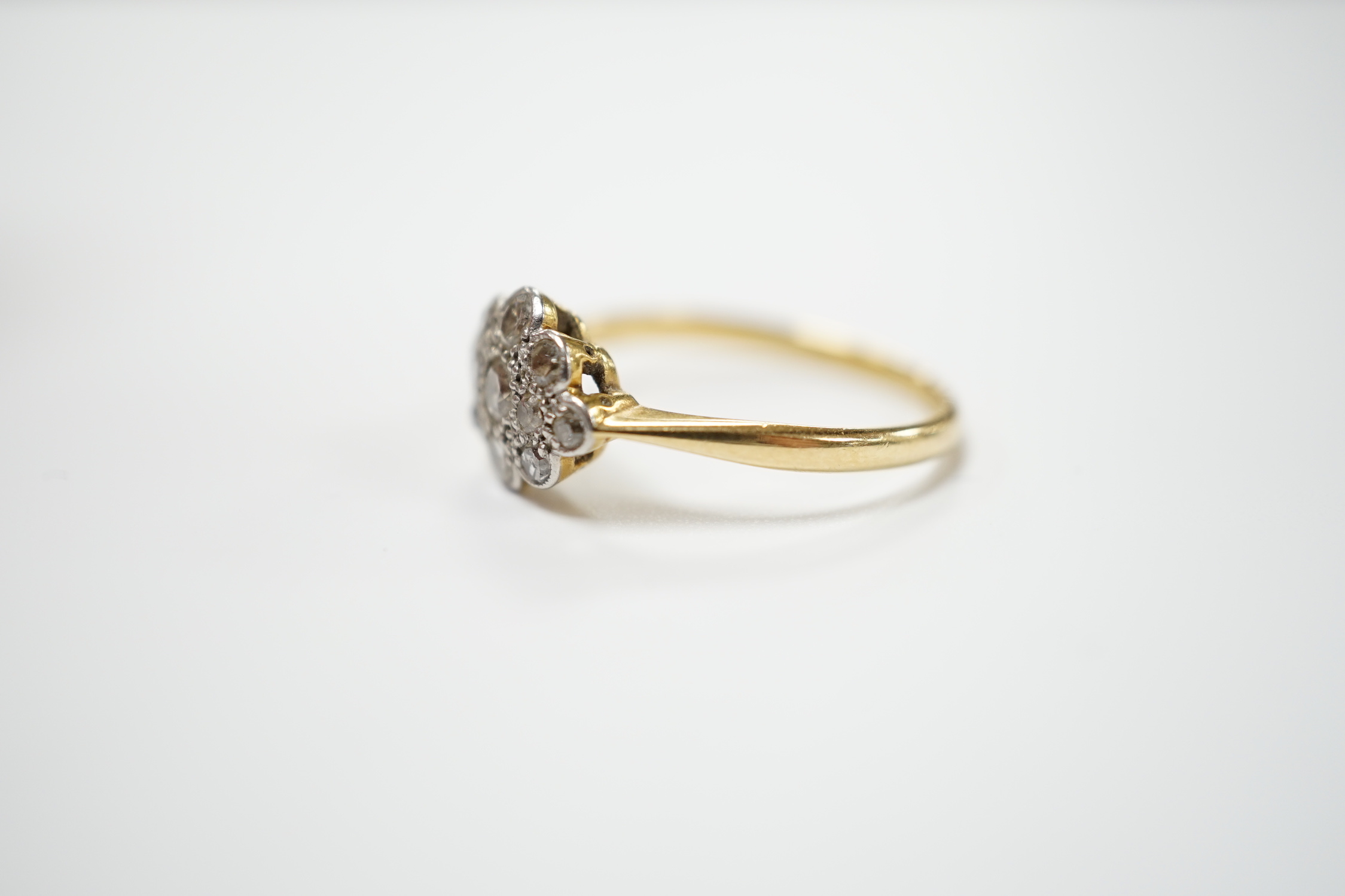 A 1920's 18ct, plat and millegrain set diamond cluster ring, size P, gross weight 3 grams.
